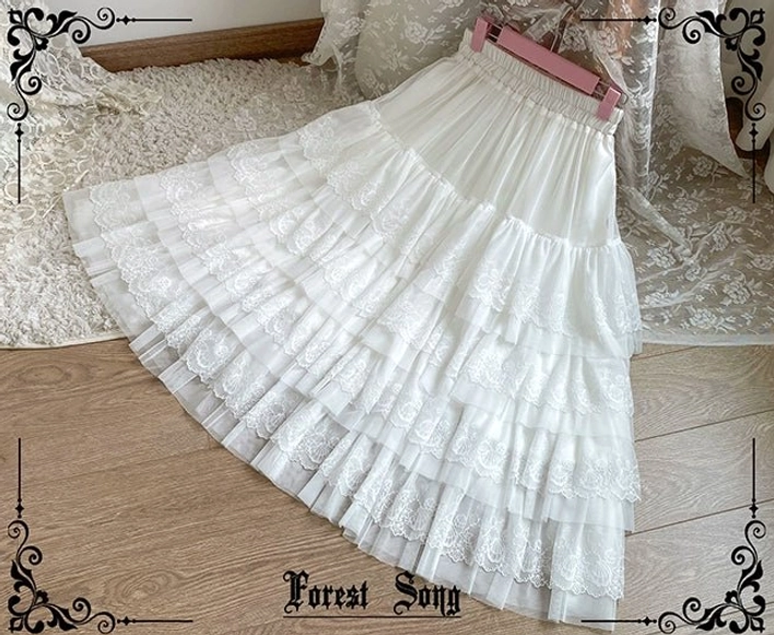 White lolita petticoat flat side lay view on wooden floor showing elastic high waistband and full multi-layered tulle ruffles with midi length construction
