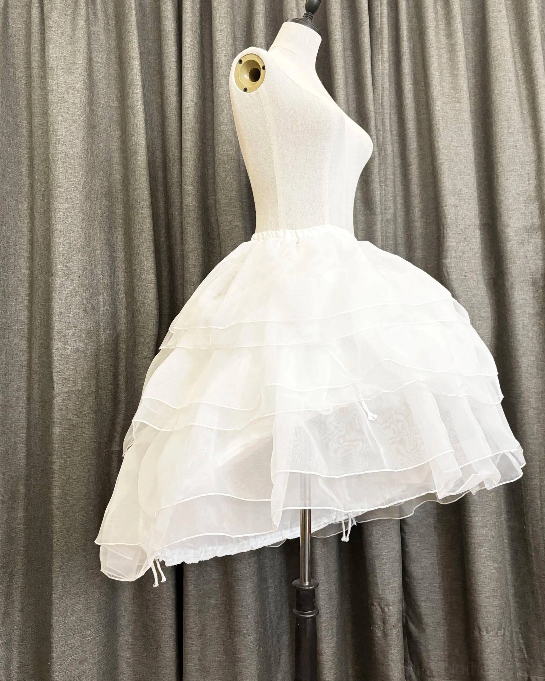 Left side view of white triple-layer Lolita petticoat showing layered tulle construction and adjustable drawstring detail at hem