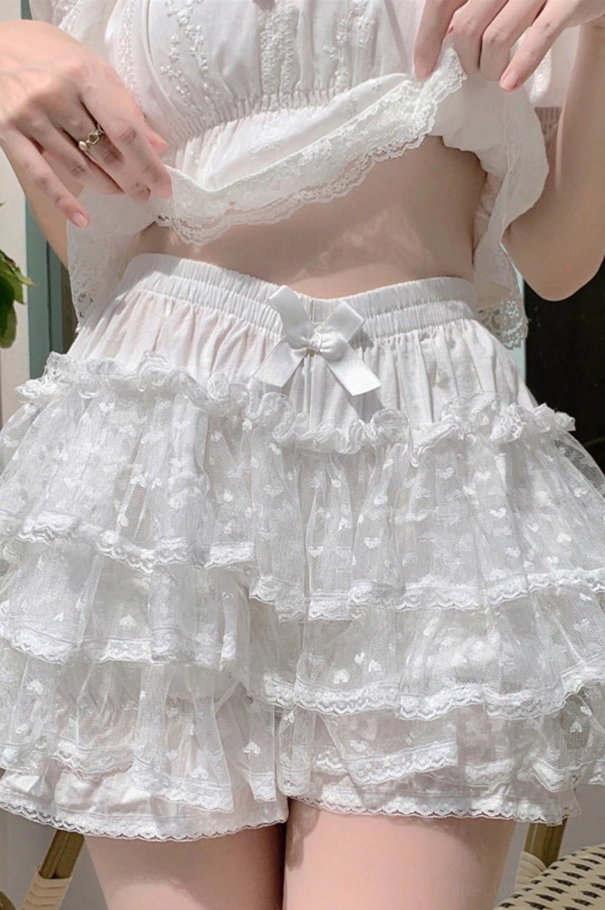 White Lolita ruffled bloomer shorts with small bow on elastic waist and multi-layered sheer ruffled hem with dot texture hand lifting cropped top waist fit demonstration