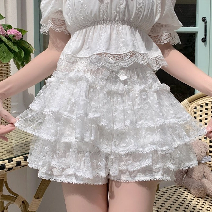 White Lolita tiered ruffled bloomer shorts with layered ruffled hem, lace trim and elastic waist with tiny bow accent close-up front waist detail view without full model