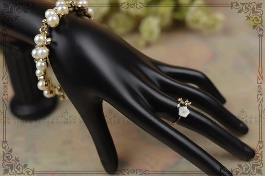 Side view of white mother-of-pearl flower Lolita ring worn with a coordinating pearl cluster bracelet