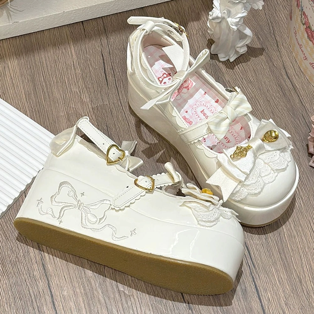 White patent leather mousse roll sweet lolita platform shoes three-quarter top-down view with heart-shaped gold buckle ankle strap and bow details