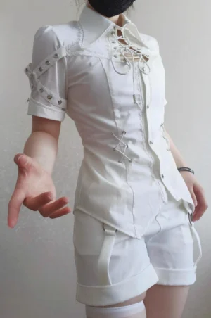 White Ouji Lolita blouse and shorts two-piece set half-body front view on model wearing white thigh-high stockings, showing pointed collar, front lace-up closure, buttoned front, decorative shoulder strap details on short sleeves with fitted waist cut