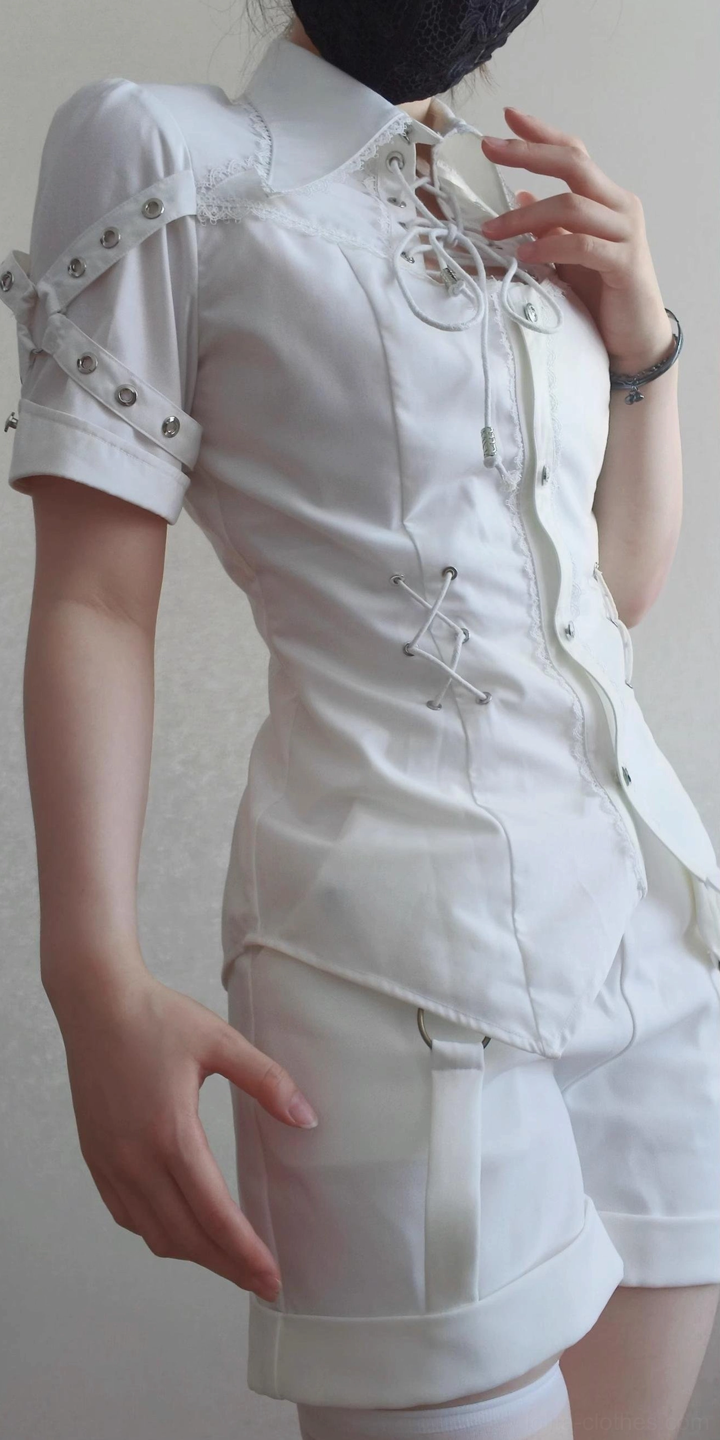 White Ouji Lolita blouse and shorts set side profile view on model with white thigh-high stockings, displaying fitted slim silhouette, front lace-up details, metal hardware decorations on sleeves, and high-waisted matching shorts