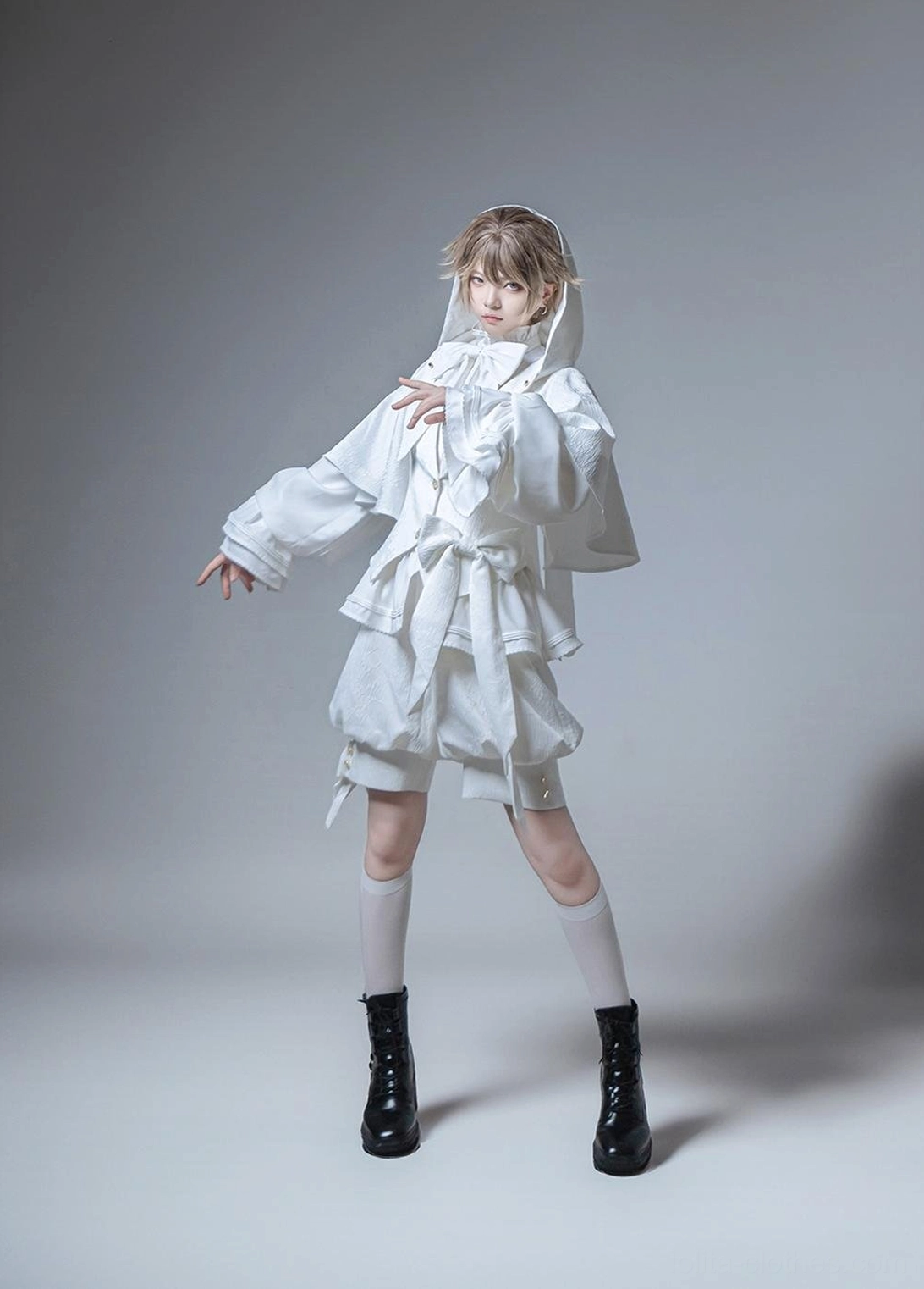 White Ouji Lolita hooded jacket and shorts set side profile showing relaxed silhouette neatly tied waist sash and fully worn hood on model in gray studio