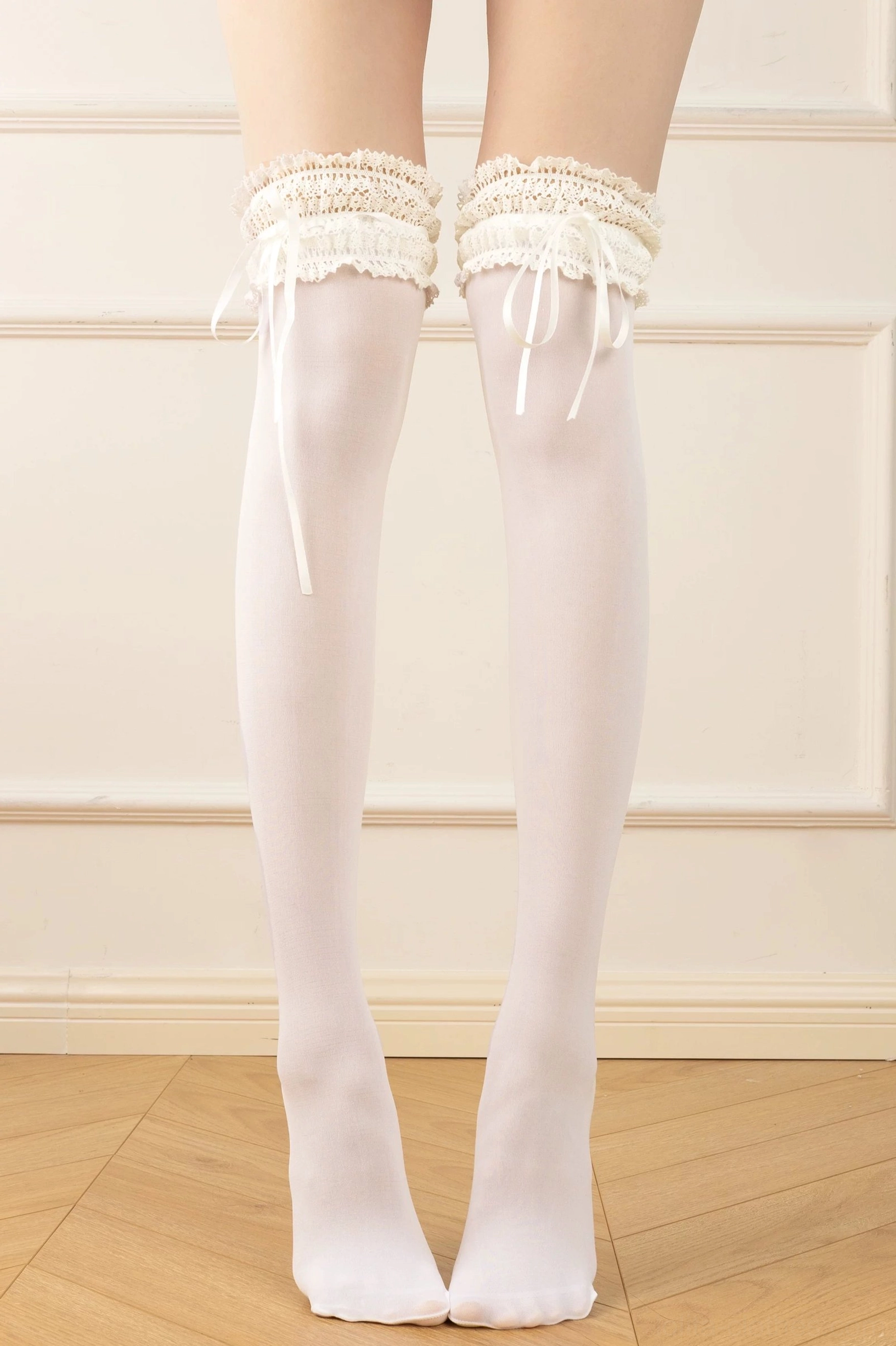 White over-the-knee classic lolita ruffle socks with cream frilled lace thigh cuff and satin ribbon bow, full leg front view on model