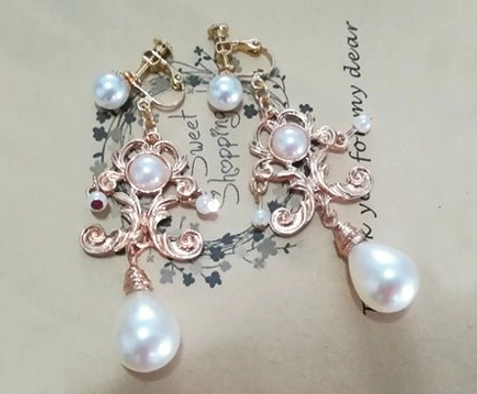 White pearl Baroque Lolita ear clips in rose gold tone with decorative scrollwork and large teardrop pearl pendants
