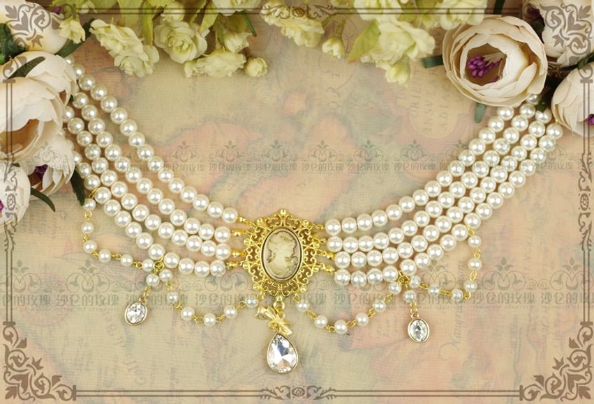 Full-length multi-layer white pearl statement choker necklace on ornate vintage frame with floral background, displaying extended pearl layers, large gold cameo centerpiece, and multiple dangling crystal and pearl accent pendants