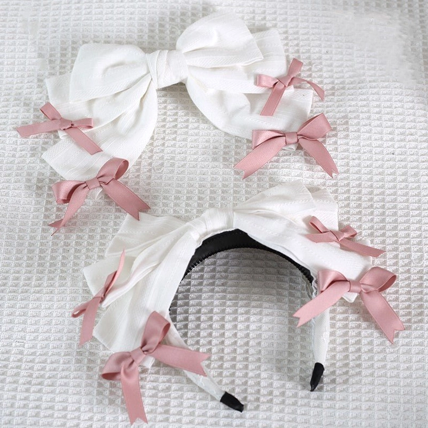 White bow lolita hair accessories set flat lay showing one headband and two hair clips decorated with pink satin small bows white waffle texture background