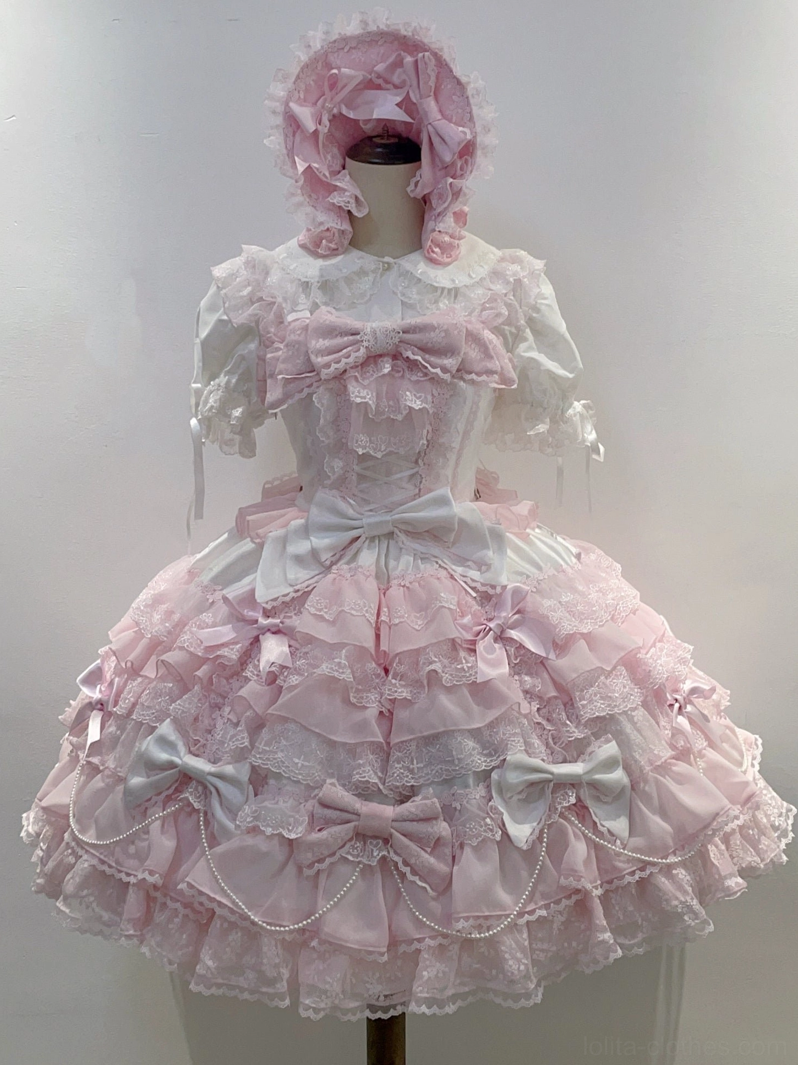 White and pink lolita jumper dress showing sweet aesthetic with multiple bows layered ruffles and romantic design elements