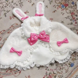 White plush Lolita cape with strong pink pearl-studded bow and rabbit ears design flat lay presentation