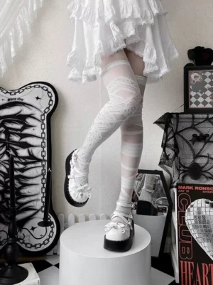 White punk lolita platform shoes with black cross buckle straps and bow detail, paired with white ruffled lace skirt and white thigh-high socks, side angle view showing thick black wedge sole
