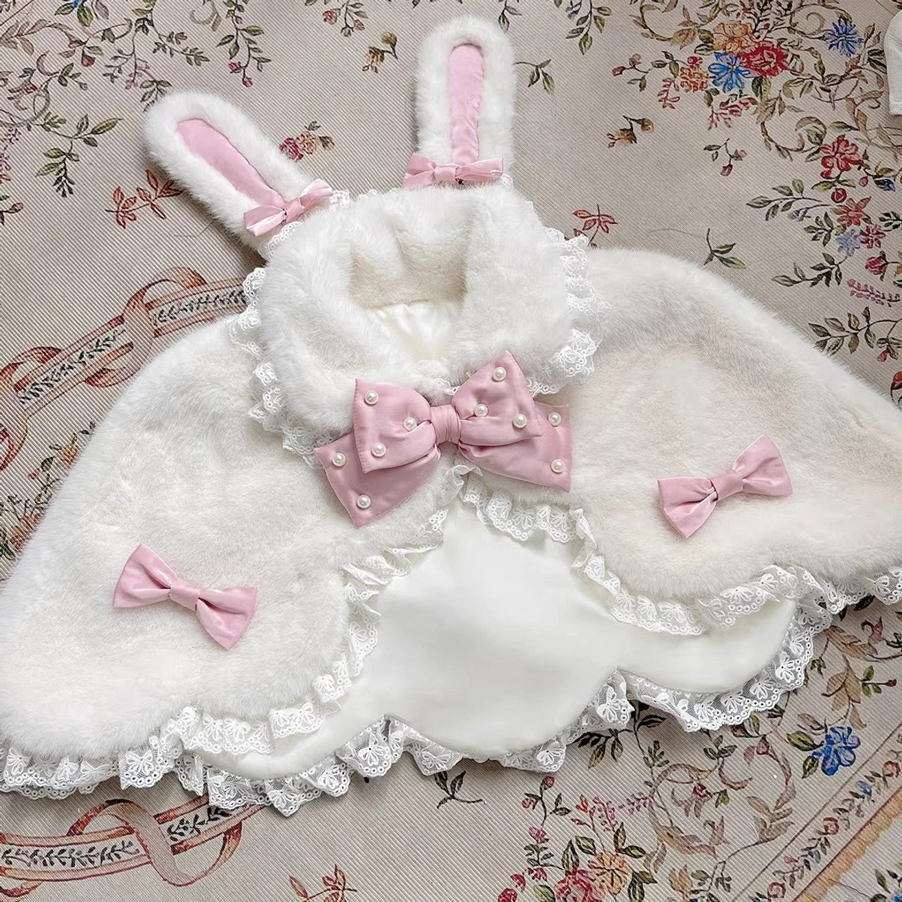 White rabbit ear plush winter Lolita cape with light pink pearl bow and lace ruffle hem flat lay display