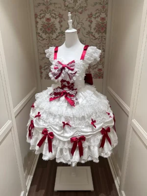 White and red sweet lolita jumper skirt dress with multiple red bows and ruffled shoulder straps, displayed on mannequin showing full tiered lace skirt