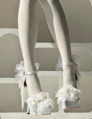 White romantic lolita platform high heel shoes featuring lace flower and feather trims, satin upper, ankle buckle strap, chunky platform heel, side static shot on mannequin with white sheer stockings