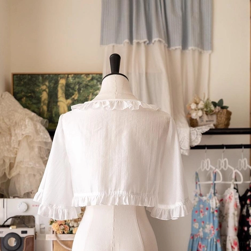 Back view of white ruffled Lolita cropped cardigan on dress mannequin, clean back design with full ruffled trim along garment hem, vintage clothing studio setting