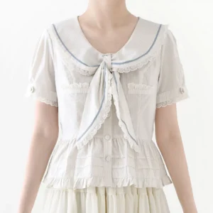 Close-up torso shot of white lolita sailor collar blouse with blue lace trim, detachable bow tie, short puff sleeves with lace trim, and ruffled peplum hem, displayed on plain white studio background