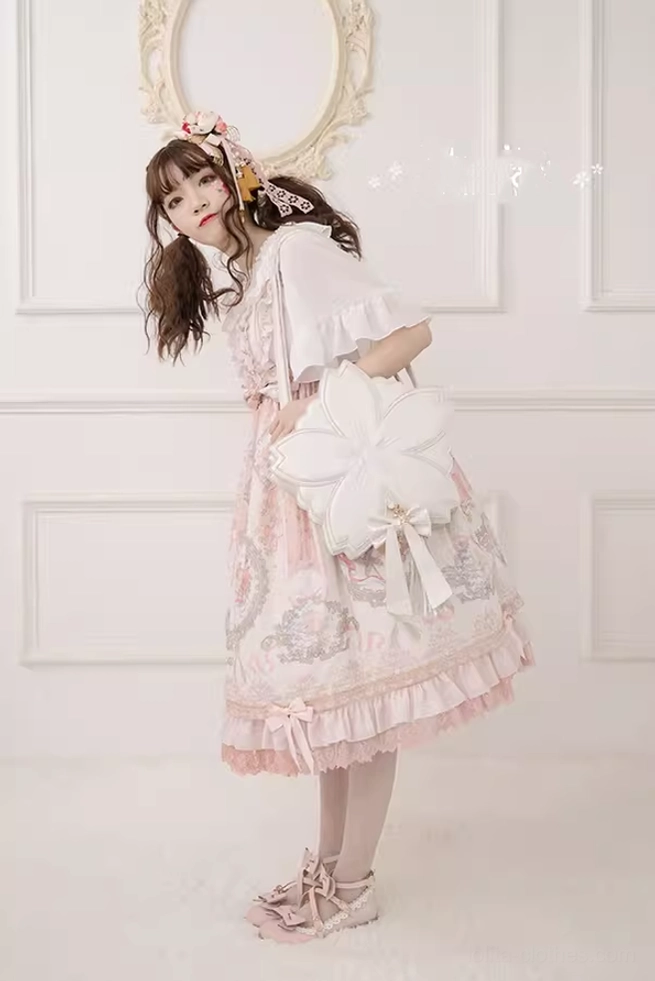 White cherry blossom lolita handbag with bowknot decoration worn with pink ruffled lolita dress side three-quarter view