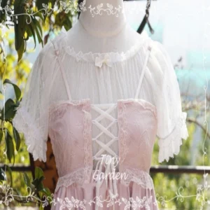 Matching sheer lace lolita inner blouse with ruffled boat neck and small bow detail, worn on dress form with pink corset-style lolita dress in outdoor garden setting, front full view