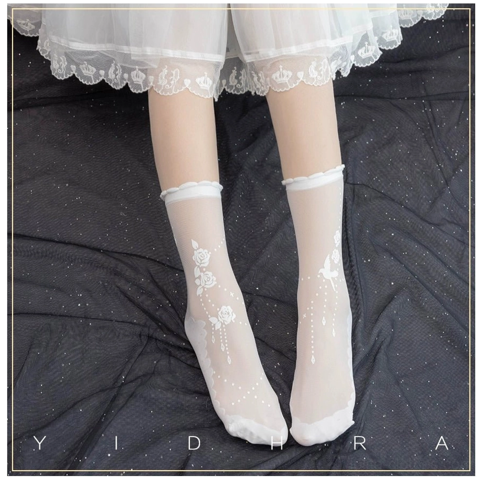 White sheer Lolita socks with subtle floral bird and dot print on dark sparkly bedding worn with lace frilly skirt hem overhead view