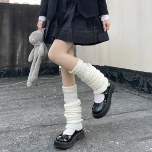 White slouchy knitted lolita leg warmers with ribbed texture worn by model in jk school uniform holding teddy bear on rooftop