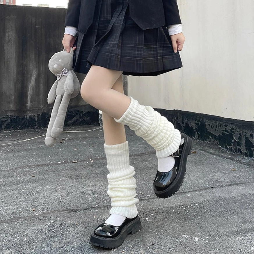 White slouchy knitted lolita leg warmers with ribbed texture worn by model in jk school uniform holding teddy bear on rooftop