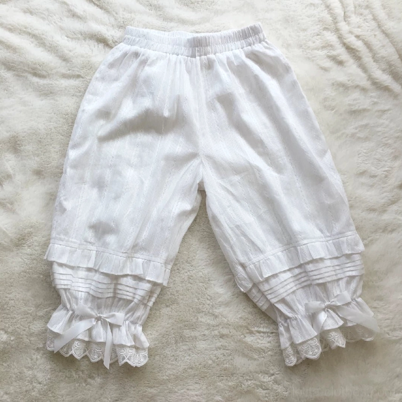 White sweet lolita jacquard cotton bloomers flat lay overhead view displaying accordion pleats elastic waist lace ruffled cuffs and satin bow accents detail