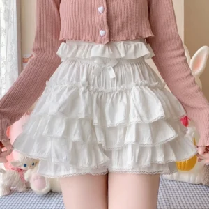 White tiered ruffled sweet lolita bloomer shorts on model half-body front view elastic high waist small front bow lace-trimmed hem authentic lolita aesthetic cozy indoor scene