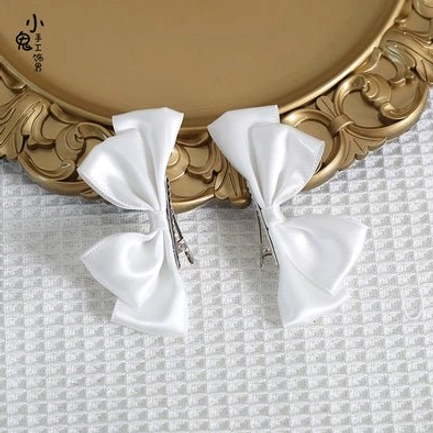 White Sweet Lolita satin bow hair clips in flat lay display on ornate golden tray and checkered fabric showing bright white bows and matching alligator hair clips