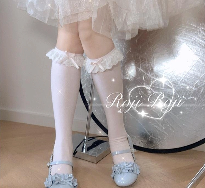 Pure white lace-trimmed sweet lolita calf-length socks with wide ruffled lace top edge and soft knit texture, seated front low-angle view with tulle frilly skirt and blue ruffled Mary Jane shoes