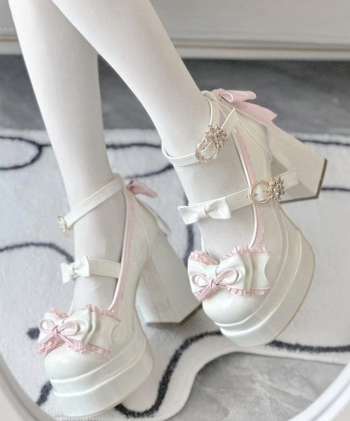 White sweet Lolita patent leather platform heels worn on-foot side view with white stockings gold heart buckles and ruffled bow details