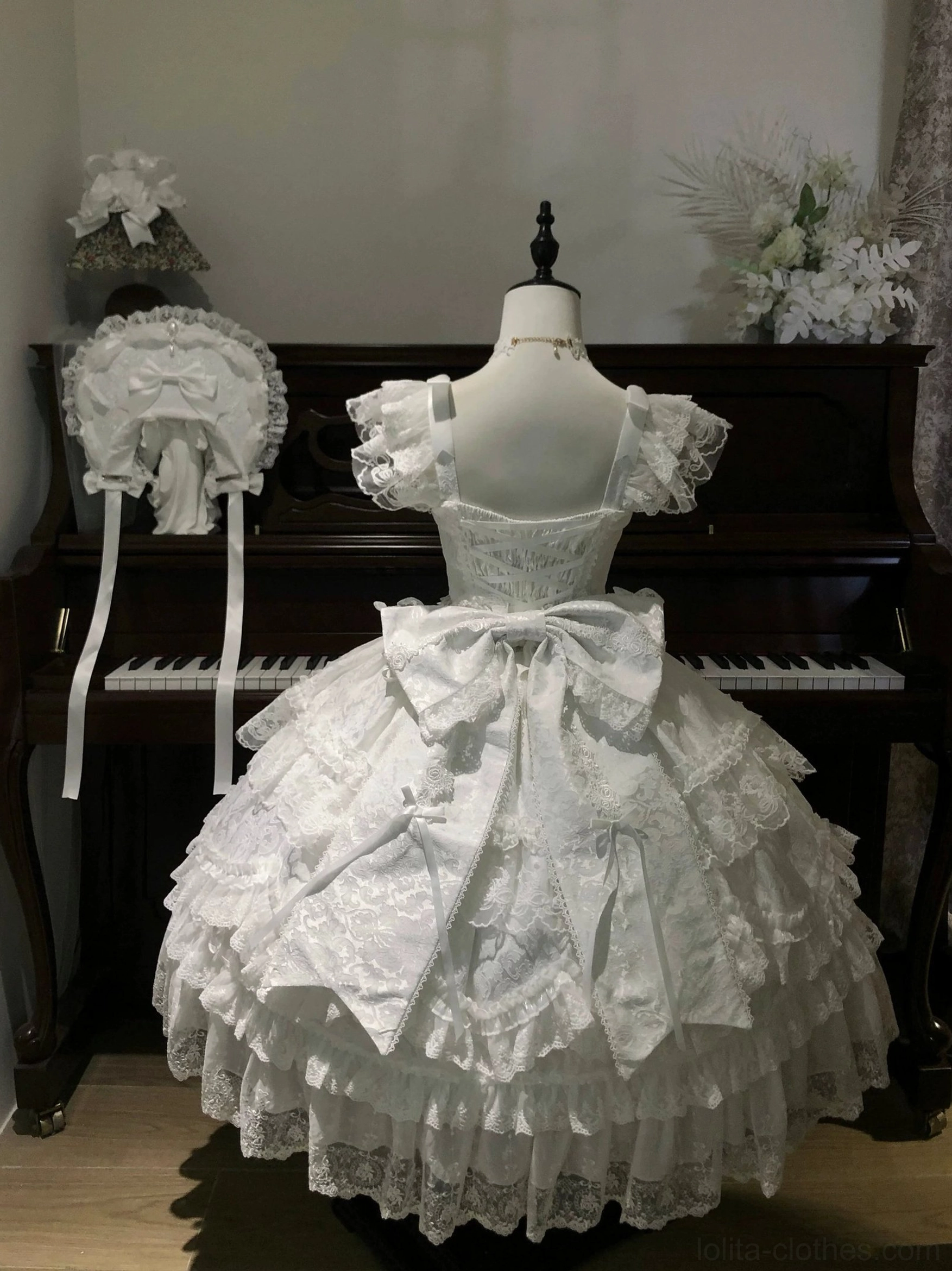 Back view of pure white sweet lolita tiered JSK dress with large back bow and intricate lace embroidery on all ruffled layers