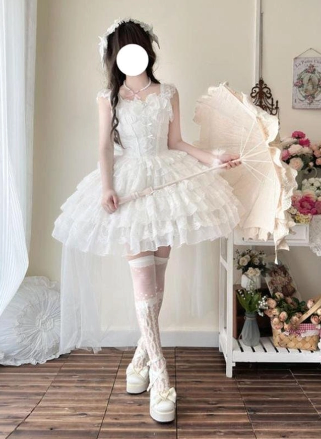 White lace-trimmed sweet lolita wedding JSK with fluffy tiered tulle skirt and sweetheart neckline, front three-quarter view with vintage parasol