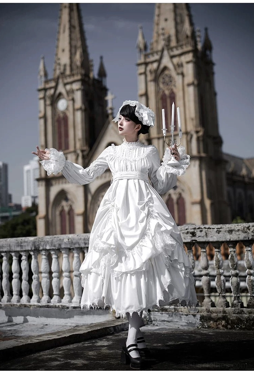White velvet gothic lolita one-piece dress front three-quarter shot with ruffled tiered skirt, lace bow collar and matching black hair bow headpiece, model holding stuffed cat plush toy