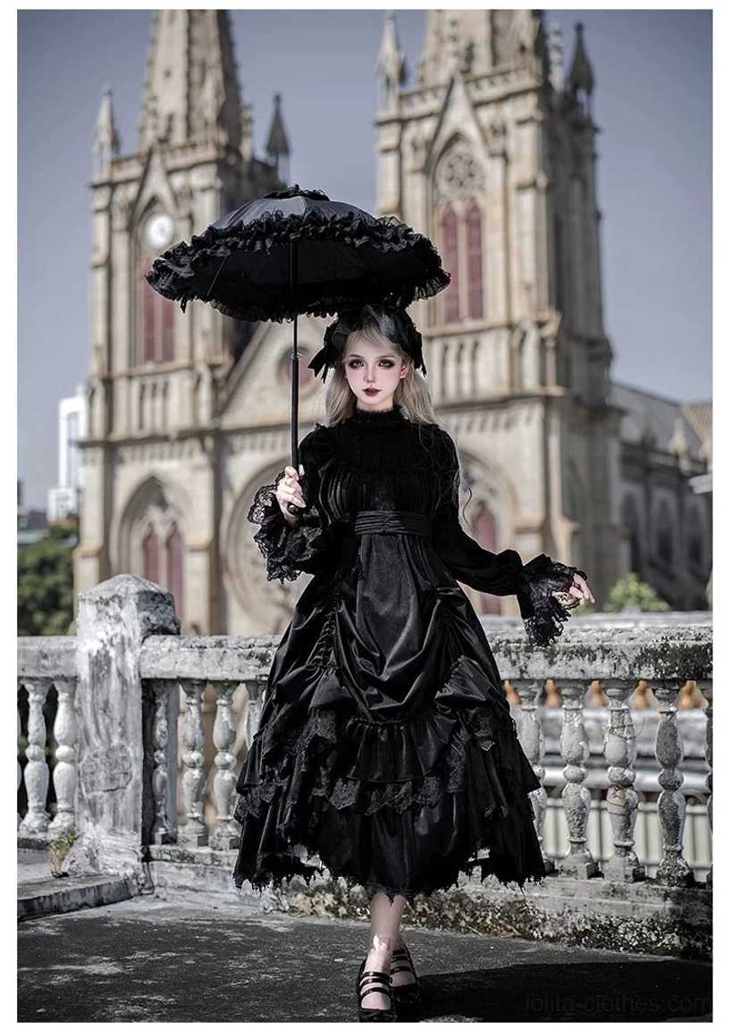 White velvet gothic lolita OP dress side three-quarter view showing midi ruffled tiered skirt, high lace collar and long bishop sleeves, model with candelabra prop at cathedral terrace