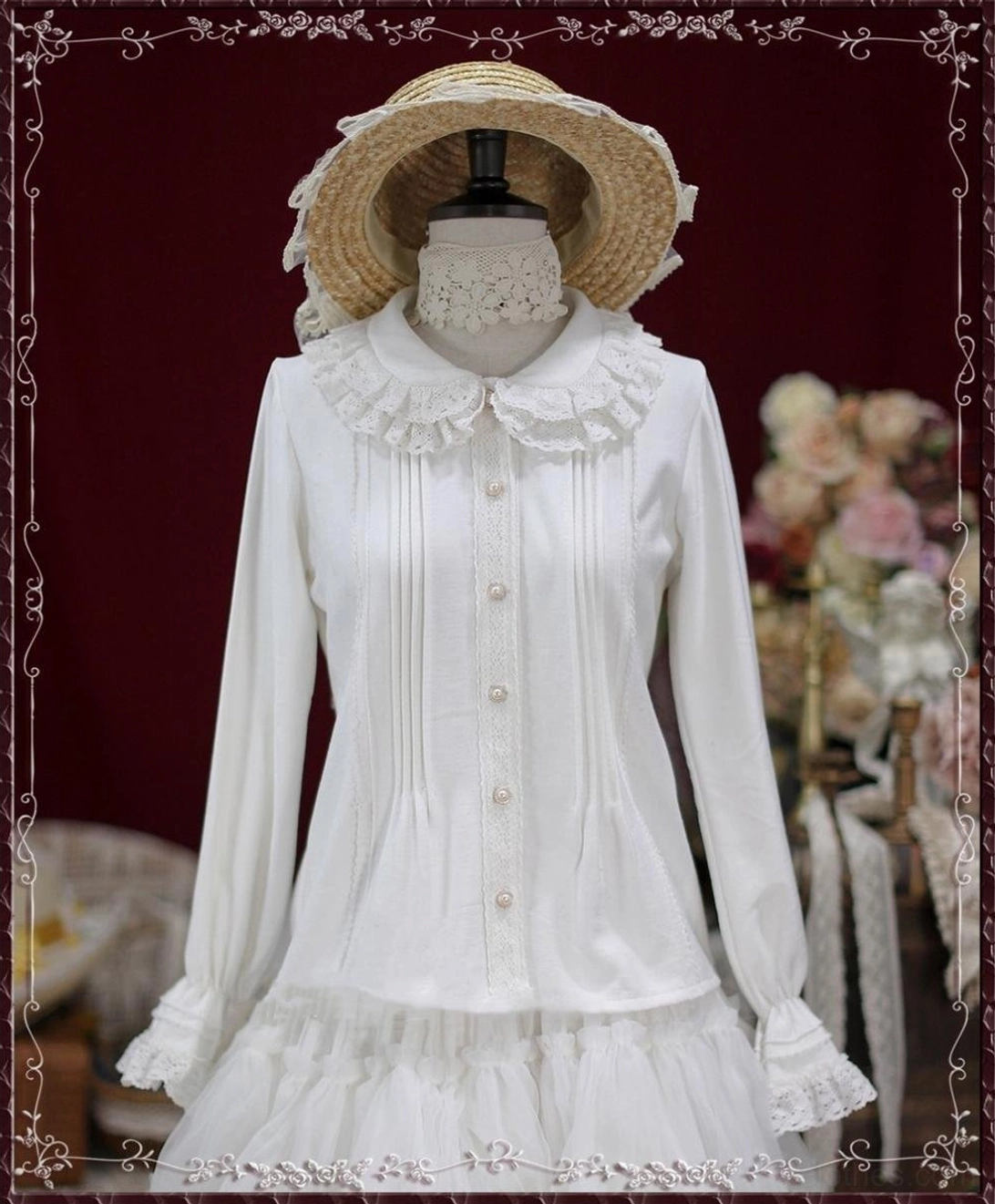 White vintage lace Peter Pan collar cotton Lolita blouse with ruffled hem and layered details frontal view on dress form with straw hat dark red floral background