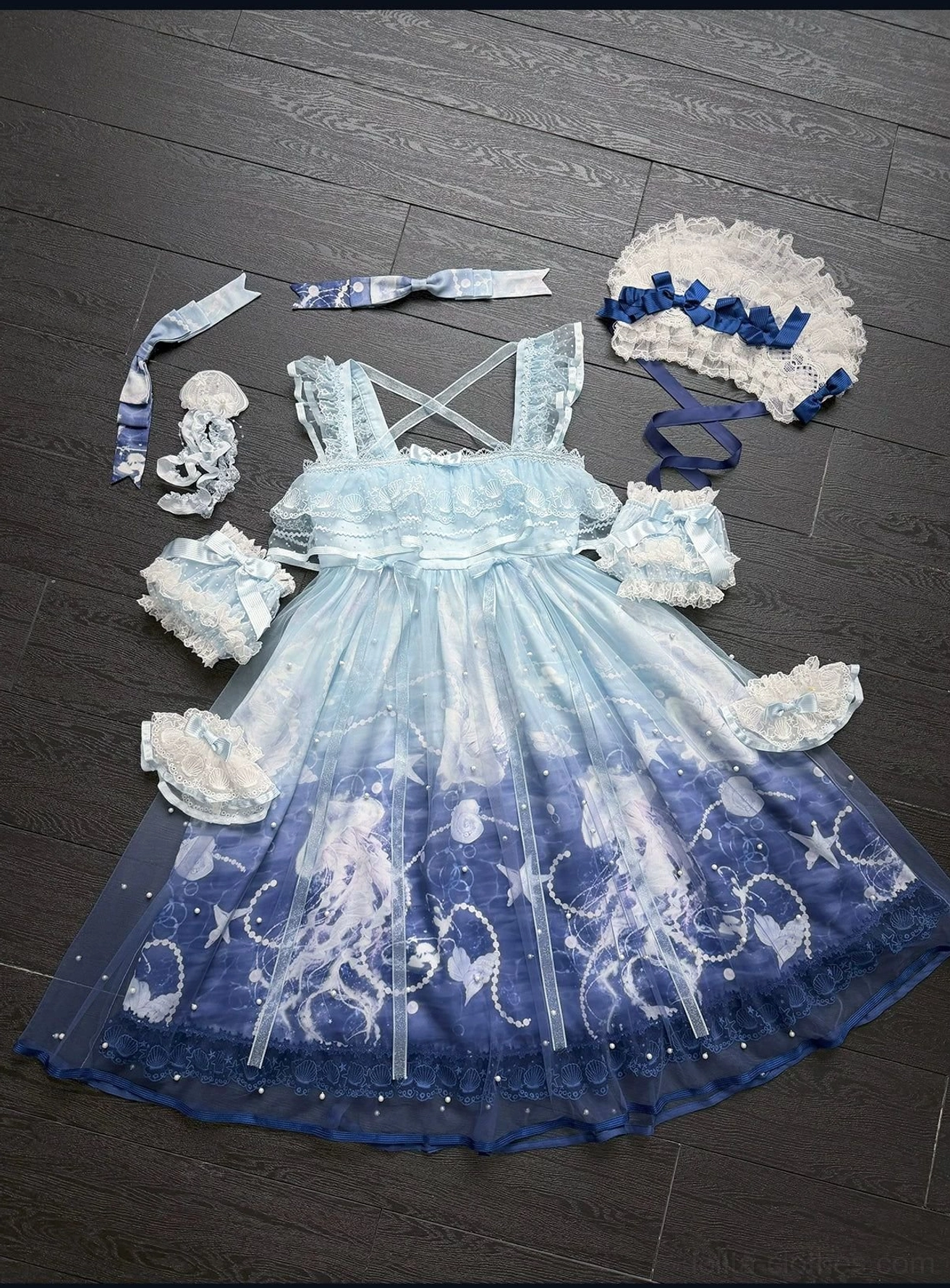 Complete jellyfish-themed sweet lolita clothing set top-down flat lay on wooden floor including gradient dress, detachable bonnet, jellyfish brooch, cross-back straps, and ruffled tulle skirt