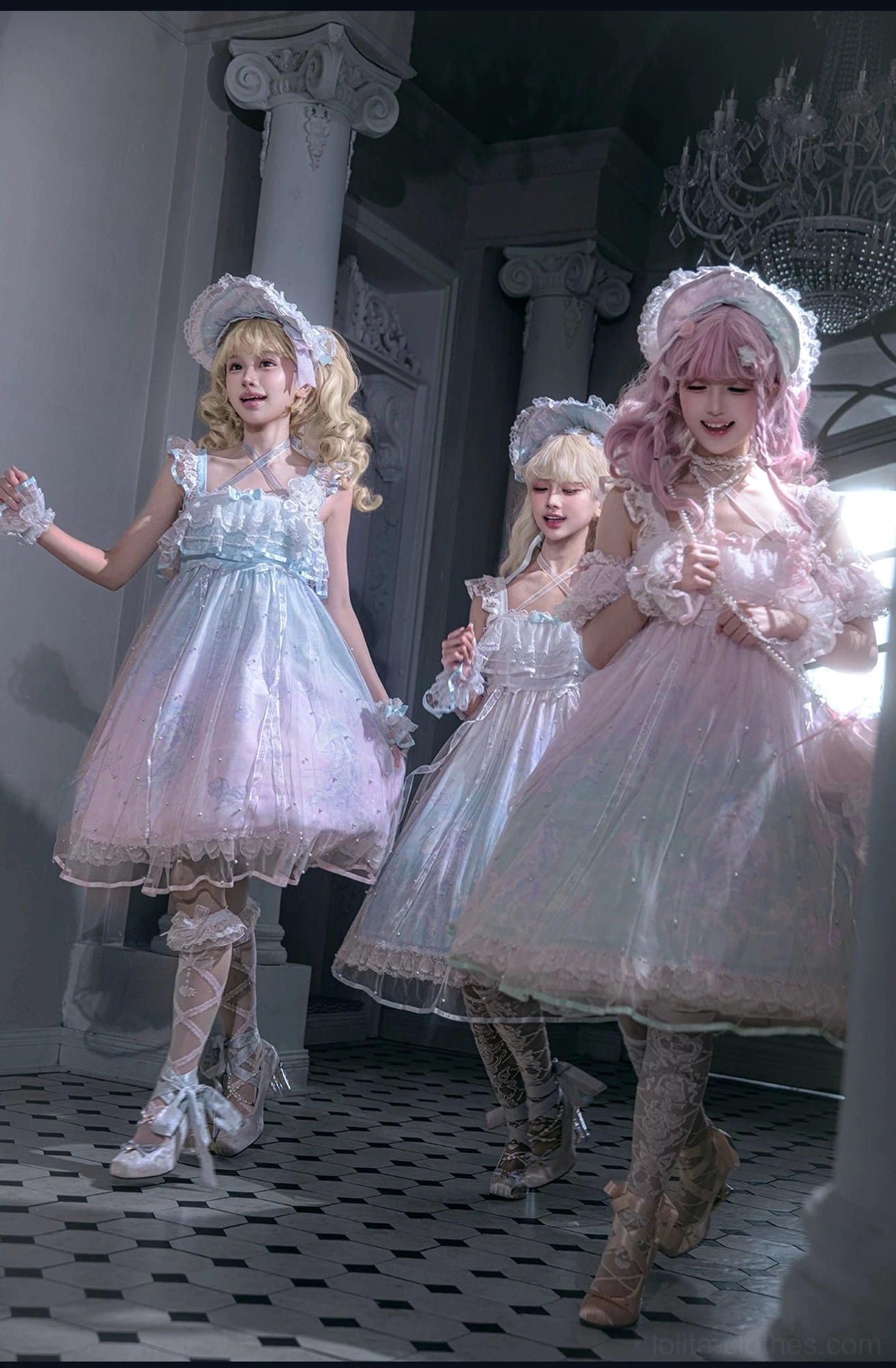 Dynamic full-body group shot of three sweet lolita models walking in vintage mansion hallway wearing sheer tulle overlays, ruffled trims, and gradient pastel headdresses