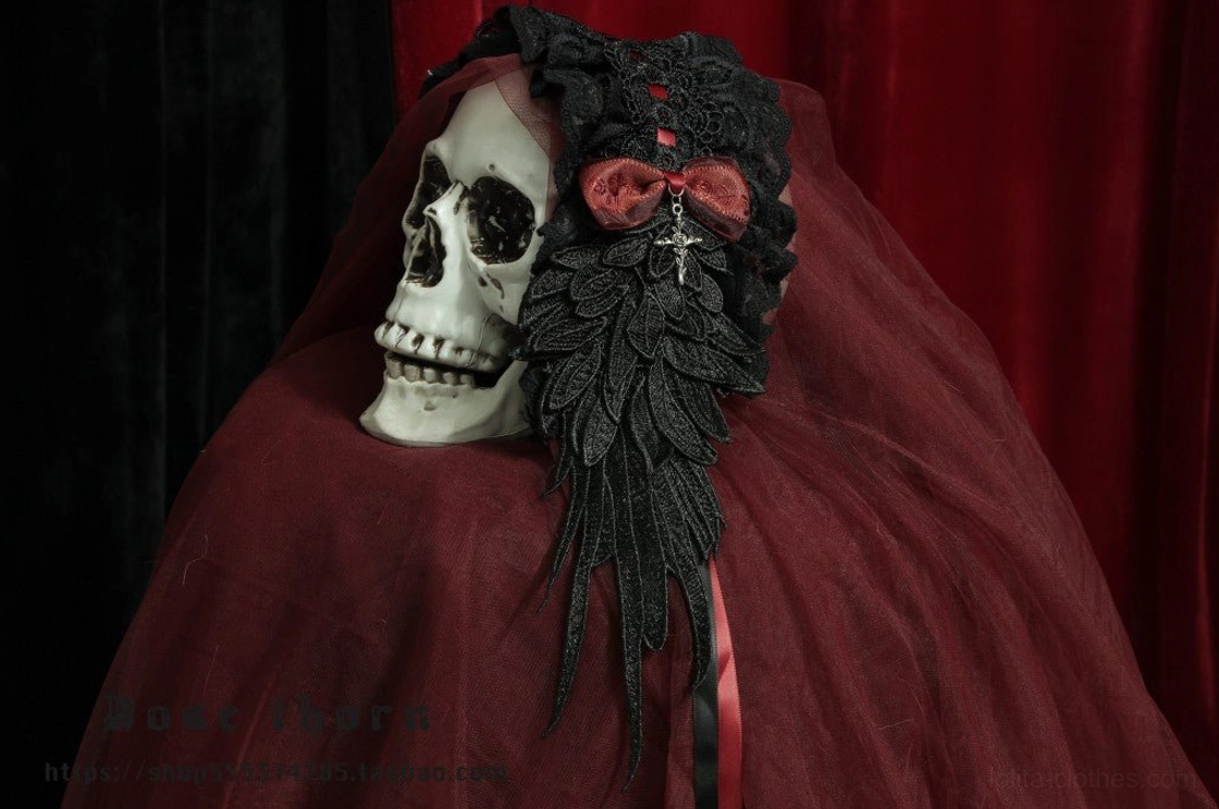 Wine red plus black gothic lolita headband with pink velvet bow decoration, black lace base with wing embroidery and silver cross pendant, burgundy backdrop skull display