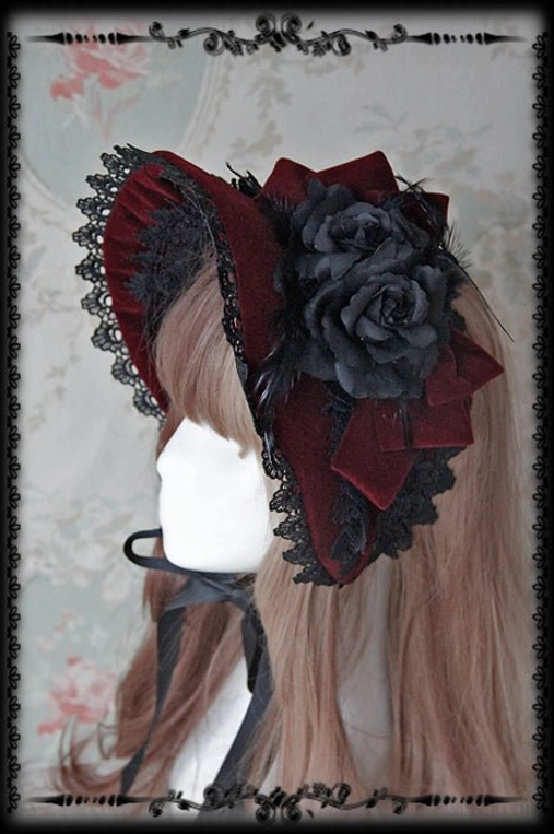 Wine red Gothic Lolita velvet bonnet featuring black lace trim and large black fabric rose bow accent, left side model wearing perspective