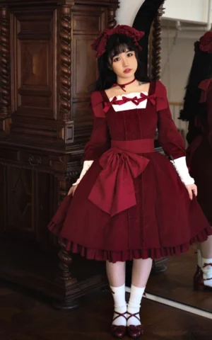 Burgundy wine red velvet classic Lolita OP dress with square neckline, front-facing full body portrait showing large waist bow and ruffled skirt hem with white cuffs and chest decorations