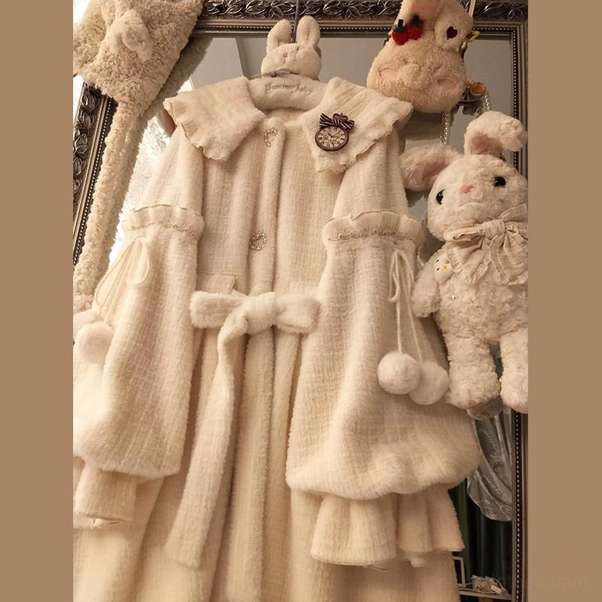 Full back view of hanging winter lolita coat showing waist bow belt, pom-pom trims, layered flared hem, collar decorative brooch, and faux fur collar detailing