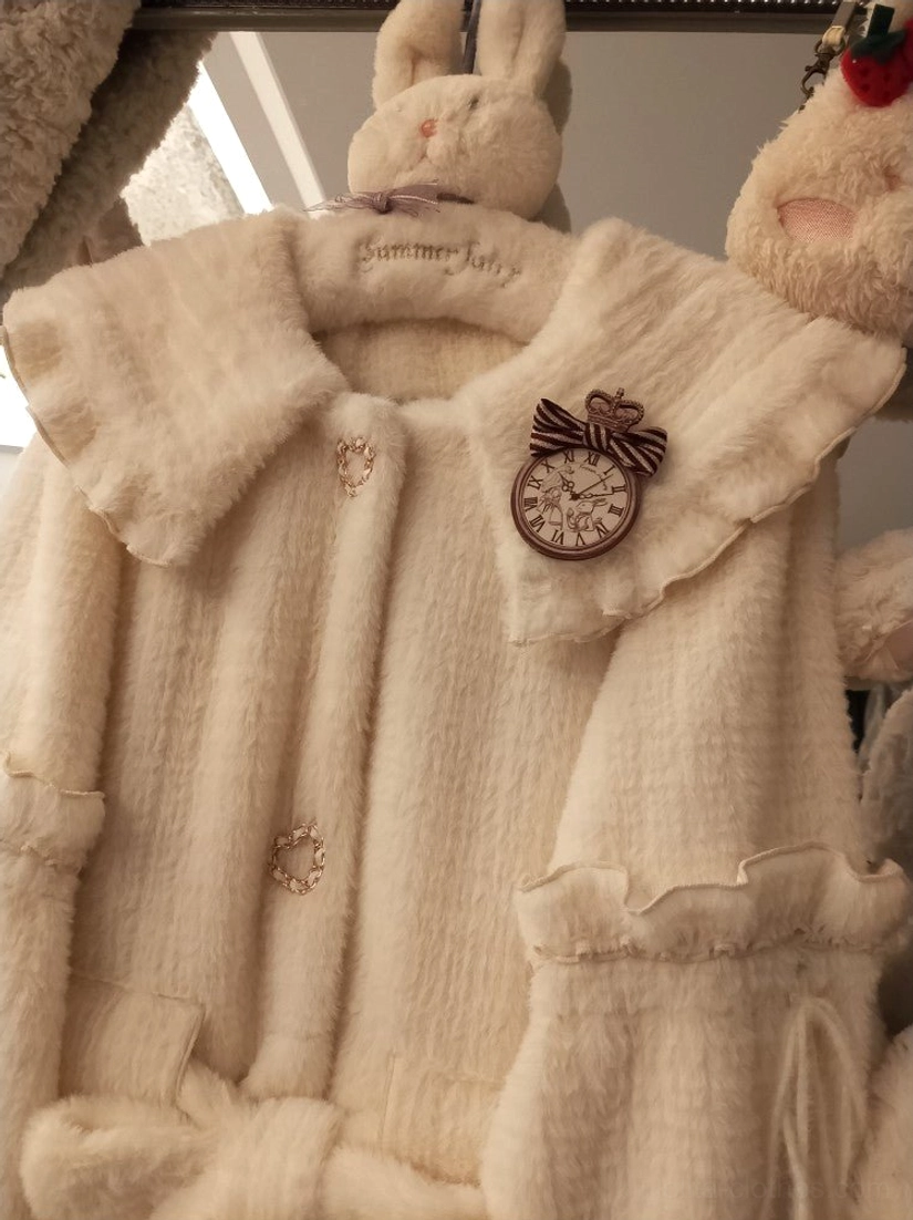 Cream puff winter lolita coat detail featuring removable fuzzy ball decorations, heart-shaped metal buttons, layered ruffles, and luxurious gold sable fabric texture