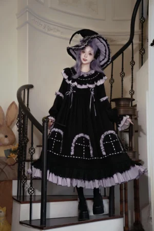 Witch Lilith Gothic Lolita OP dress with ruffled collar and medieval window embroidery, worn with authentic witch hat on model with pastel purple hair, three-quarter front view on vintage staircase