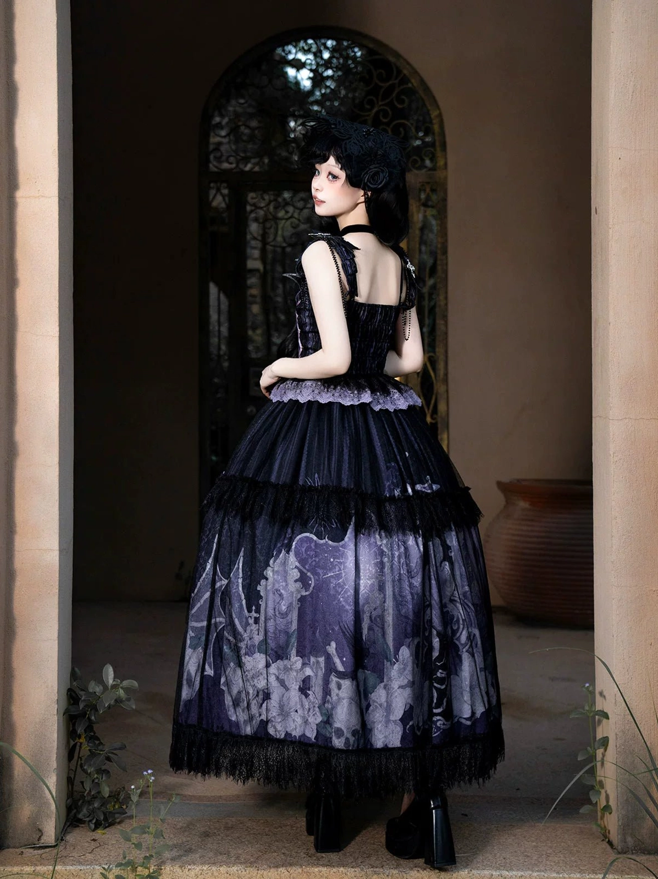 Withered Bone Gothic Lolita set back view featuring shirred elastic back bodice open design layered ruffled tulle skirt with matching skeleton floral prints on model in outdoor porch scene