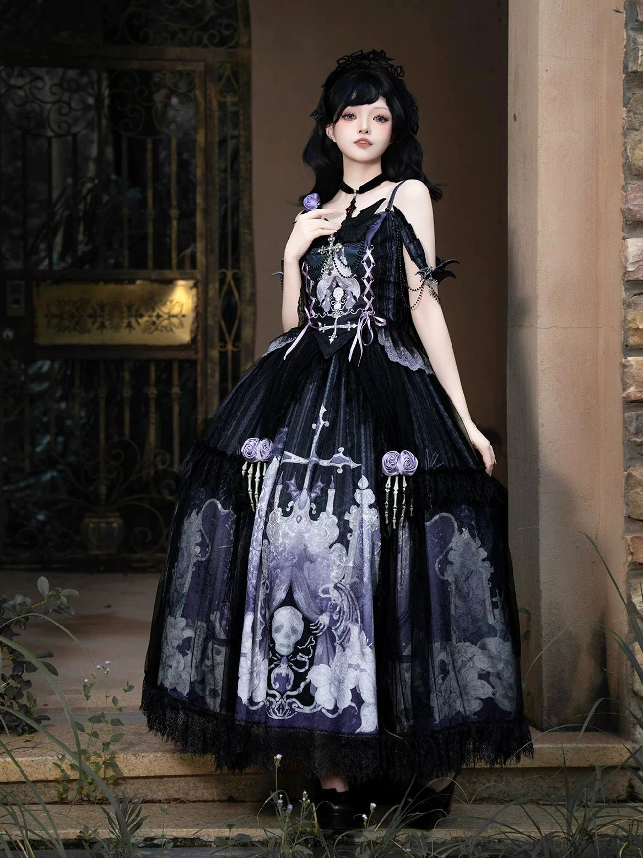 Withered Bone Gothic Lolita slip dress front three-quarter standing view model black-purple color scheme skull vintage pattern prints skeleton hand rose trim skirt waist layered tulle movement outdoor metal gate