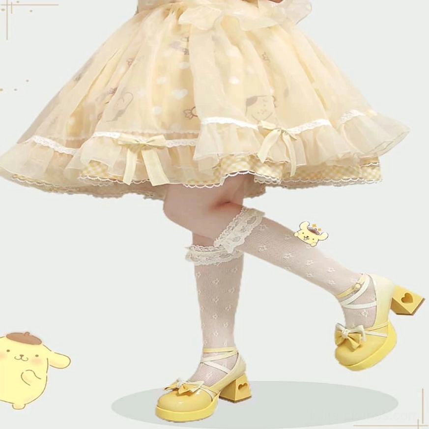 Side low-angle product view of yellow Sweet Lolita platform heels featuring cross ankle strap bow, heart-shaped block heel cutout, worn with lace-trim knee-high socks and ruffled Lolita tutu coordination