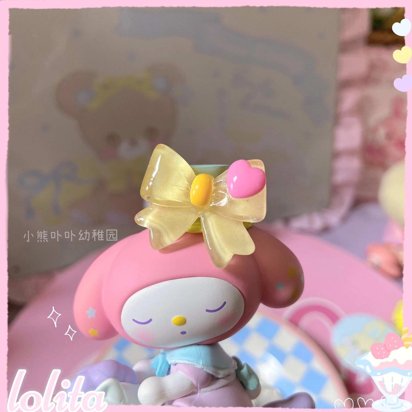 Yellow satin bowknot decorative lolita ring with pink heart resin detail displayed on My Melody Sanrio figure showcasing pastel sweet lolita aesthetic