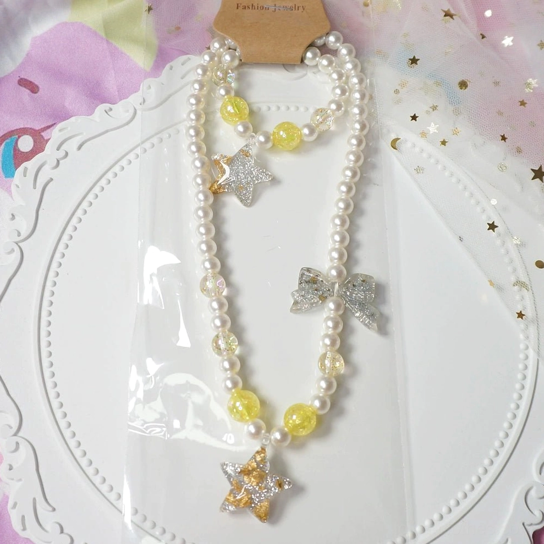 Yellow star gradient pearl choker necklace and beaded bracelet lolita jewelry set displayed on white lace tray with starry backdrop